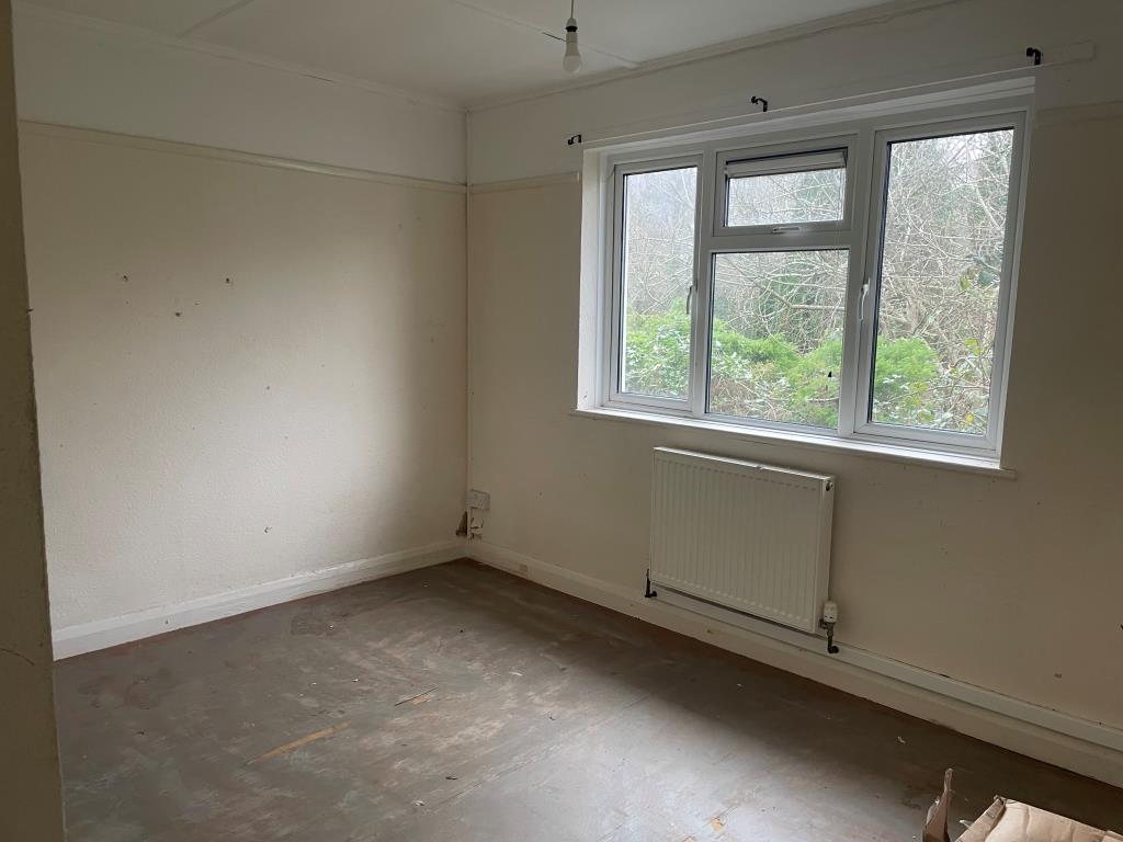 Lot: 159 - SEMI-DETACHED BUNGALOW - Bedroom with rear window looking onto overgrown garden